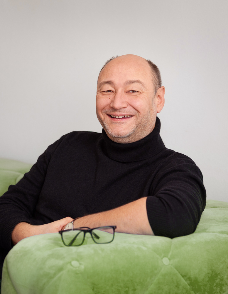 Portraitbild von Thomas Schweinschwaller, sitzend auf Sofa